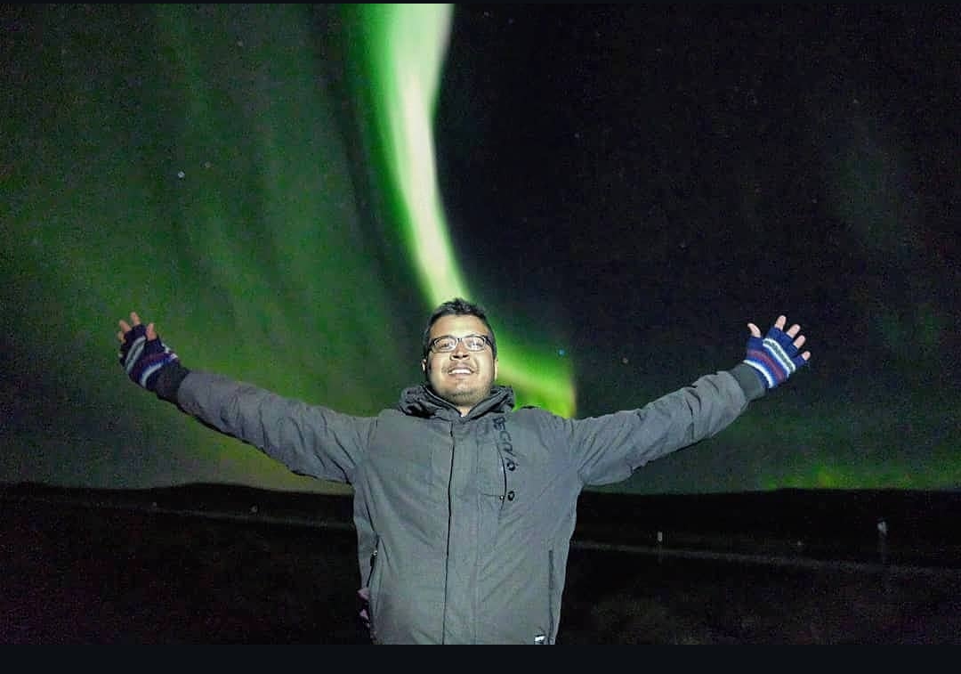 Traveller with arms outstretched beneath the Northern Lights